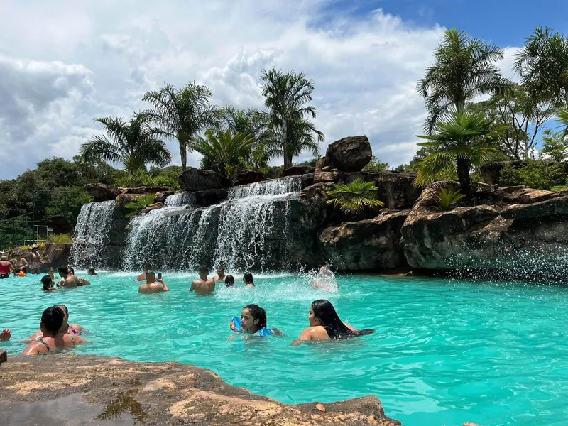 Família na água turquesa da piscina de cascata